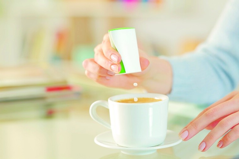 Frau fügt Süßstoff in Kaffee