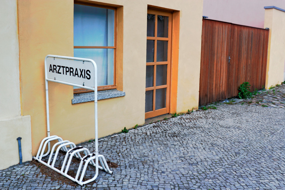 Verlassenes Gebäude mit einem Fahrradständer mit Beschriftung Arztpraxis davor