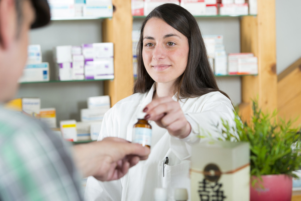 PTA reicht einem Kunden ein Arzneimittel über den HV-Tisch