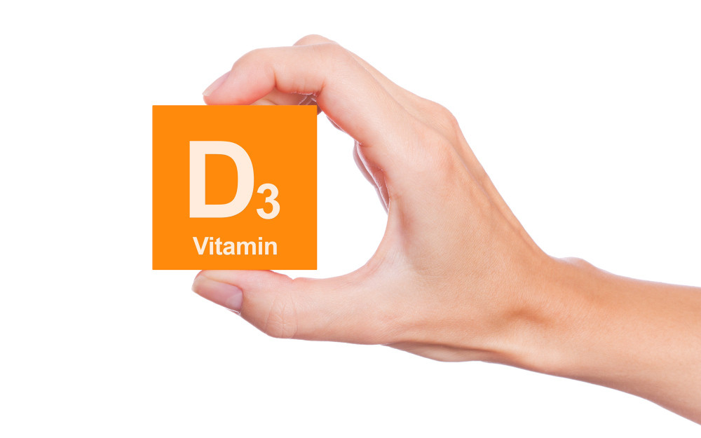 Hand hält orangefarbenes Quadrat mit Aufschrift D3 Vitamin