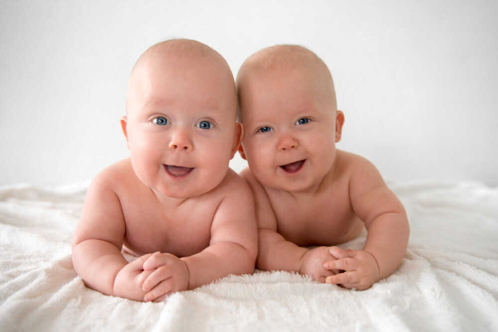 Zwillingsbabys liegen auf weißer Decke