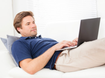 Mann mit Laptop auf dem Sofa