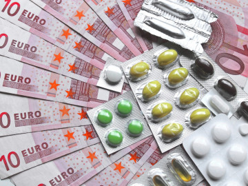 Fächer aus Zehn-Euro-Scheinen, auf dem verblisterte Medikamente liegen.